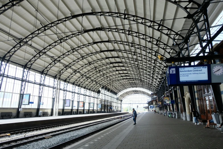 a train station with people walking on the platform, by Schelte a Bolswert, unsplash, bauhaus, canopies, 2000s photo, square, maintenance photo