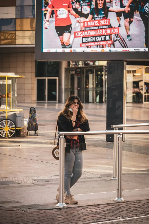 a woman standing at a metal barricade next to a tv