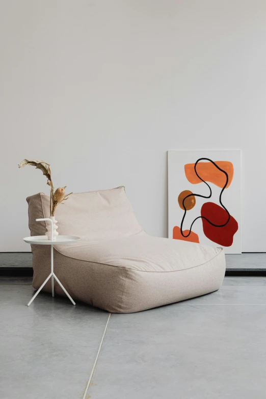 a bean bag chair sitting on top of a cement floor, poster art, inspired by Isamu Noguchi, unsplash, light beige pillows, poppy, outlined art, in a white room