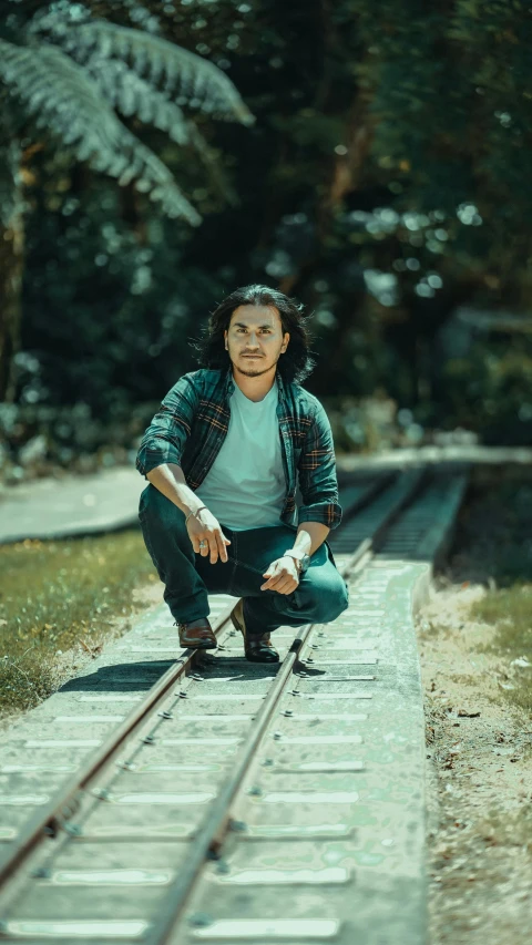 a man is crouching down on a train track