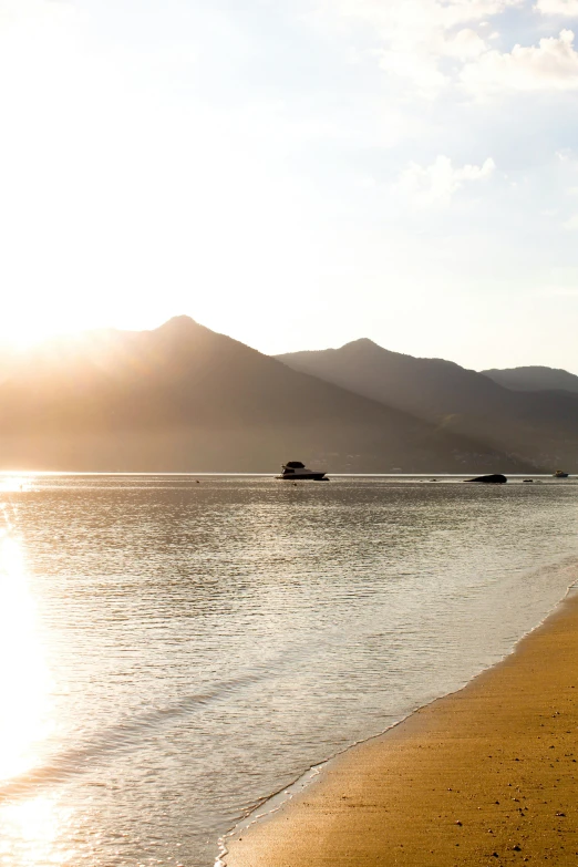 a man standing on top of a sandy beach next to the ocean, sun rises between two mountains, vietnam, subtle detailing, boats in the water