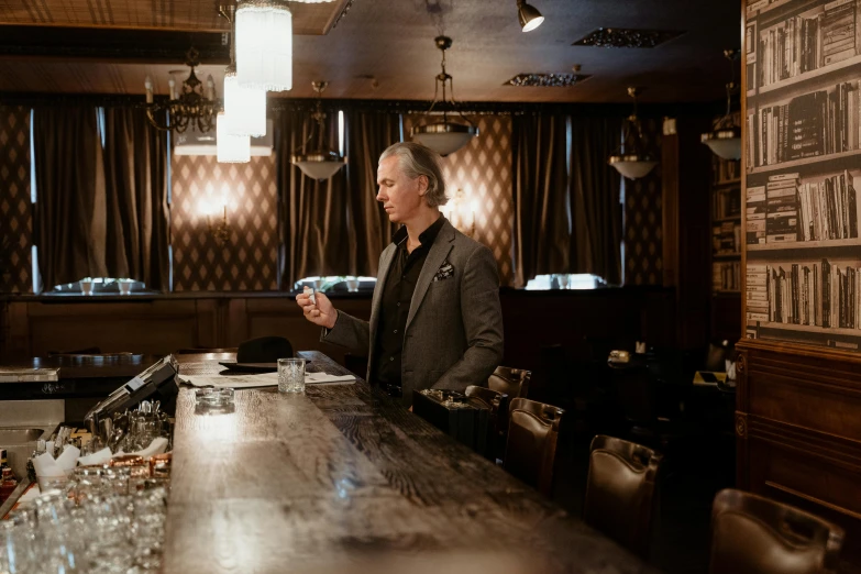 a man standing at a bar holding a drink, by Jesper Knudsen, happening, jimmy page, shot on alexa, jordan peterson, promotional image