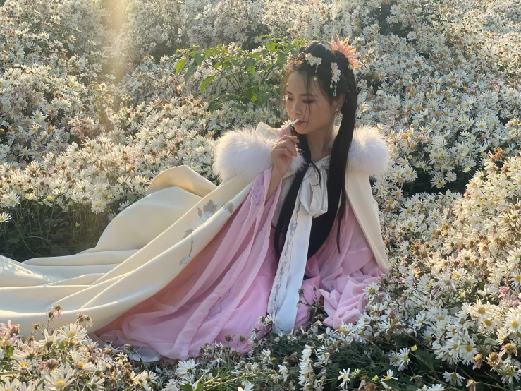 a woman wearing white and pink dress is sitting on the ground