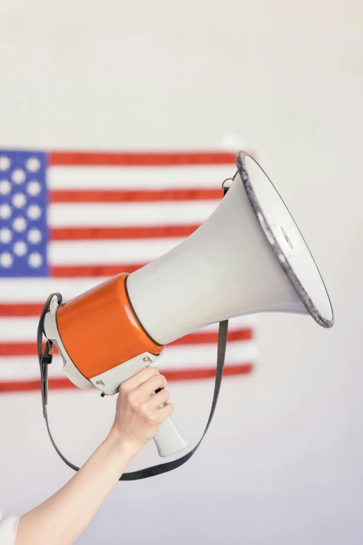 a woman holding a megaphone in front of an american flag, a colorized photo, shutterstock, ilustration, frank moth, no - text no - logo, speech