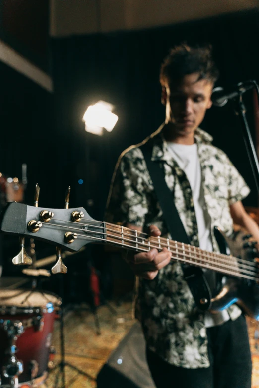 a man that is playing a guitar in a room, pexels, photorealism, bass drum, performing a music video, teenager, slight smirk