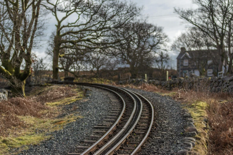 a train track with a house in the background, by Andrew Allan, unsplash, photorealism, curved, shap, ash thorp, panoramic