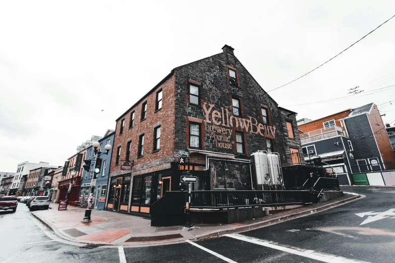 a tall brick building sitting on the side of a road, yellows and reddish black, beer, abcdefghijklmnopqrstuvwxyz, overview