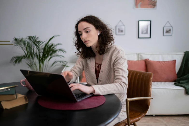 a woman sitting at a table using a laptop computer, pexels contest winner, performing, avatar image, brown, professional image