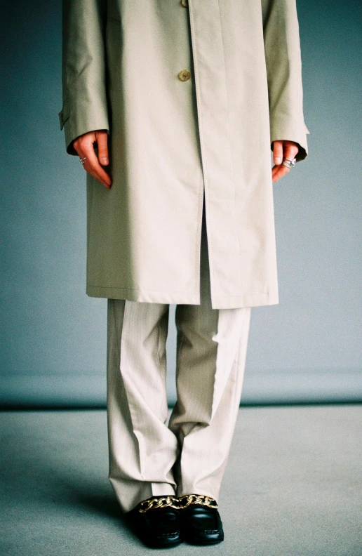 a man in a trench coat standing with his hands in his pockets, an album cover, by Yasushi Sugiyama, unsplash, large pants, light grey, offwhite, ( ultra realistic )