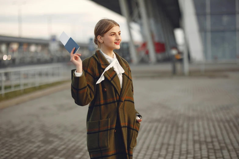 a woman in a coat is holding a book, pexels contest winner, passport, girl wearing uniform, handsome girl, thumbnail