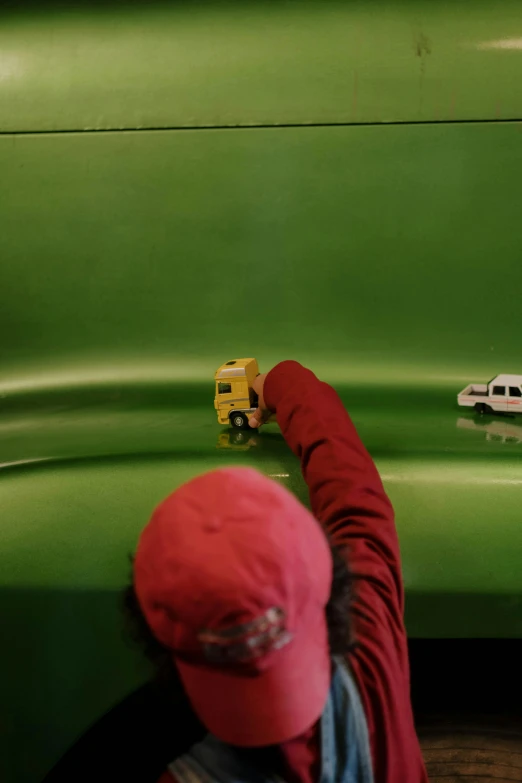 a person with a red cap on is playing with small toy cars