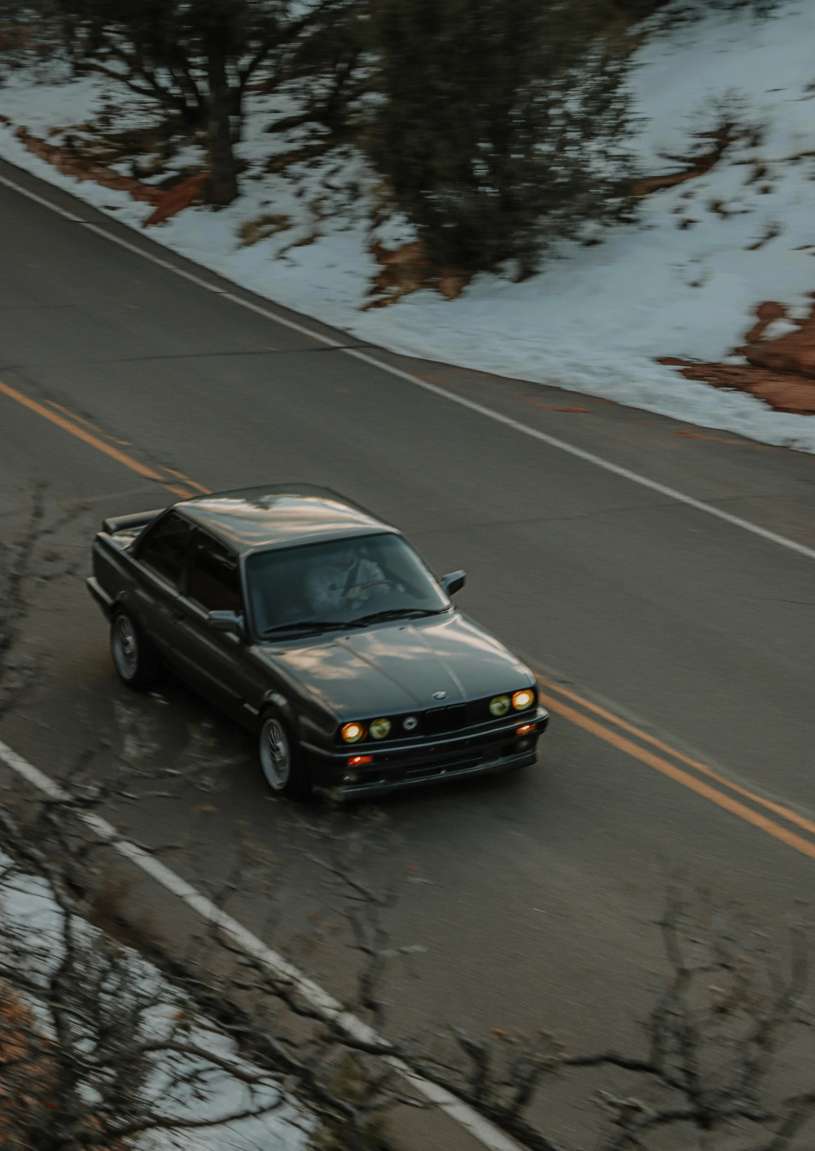 a brown car is driving down a road