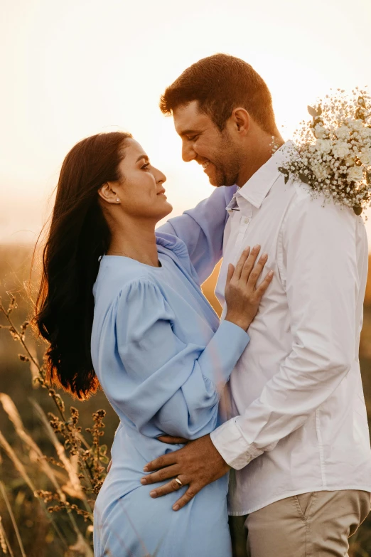 a man and woman standing next to each other in a field, pexels contest winner, beautifully soft lit, holding flowers, attractive woman, blue