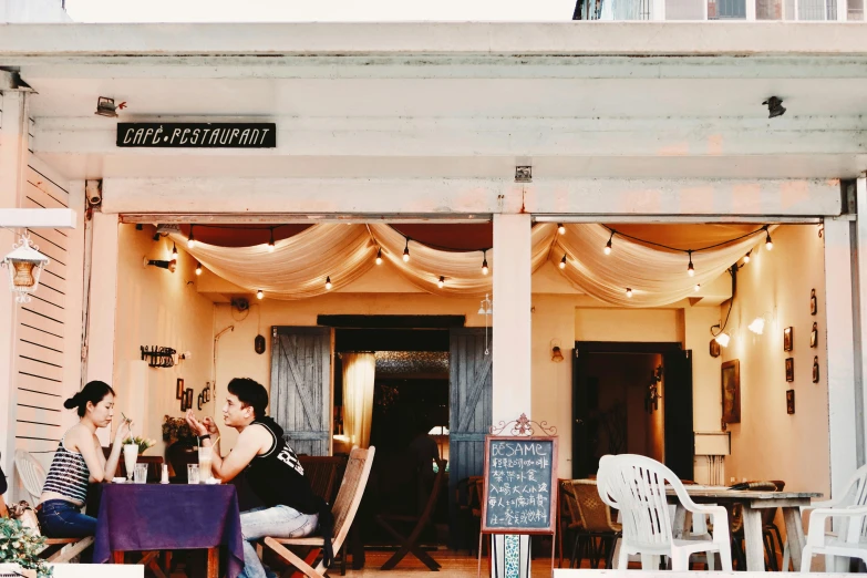 two women are sitting at a table in front of a house