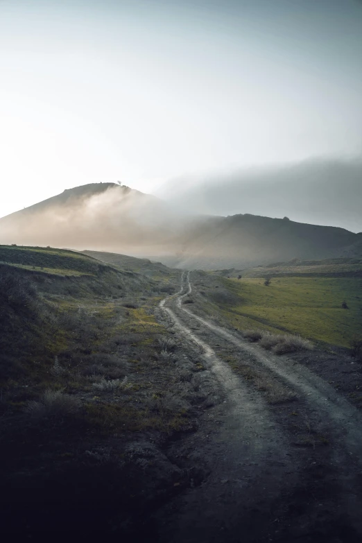 a road on the side of the mountains in fog