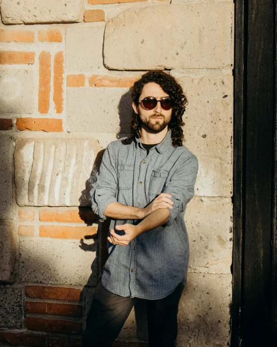 man standing in front of wall posing with sunglasses