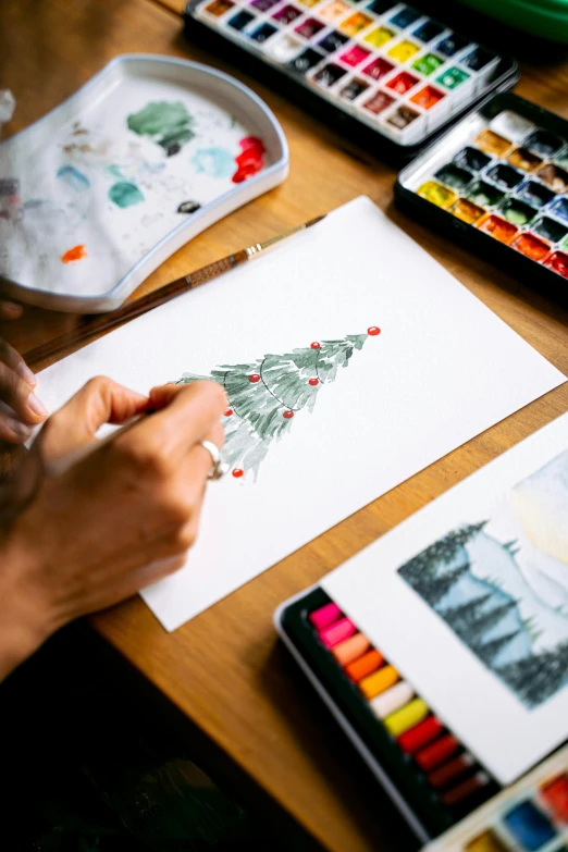 someone drawing and painting a christmas tree on paper