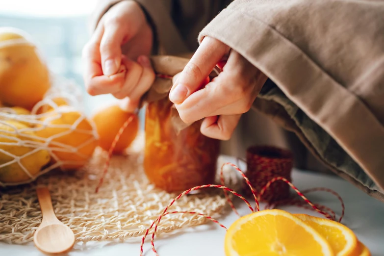 a close up of a person putting something in a jar, pexels contest winner, process art, orange ribbons, organic ornaments, fruit, stitching