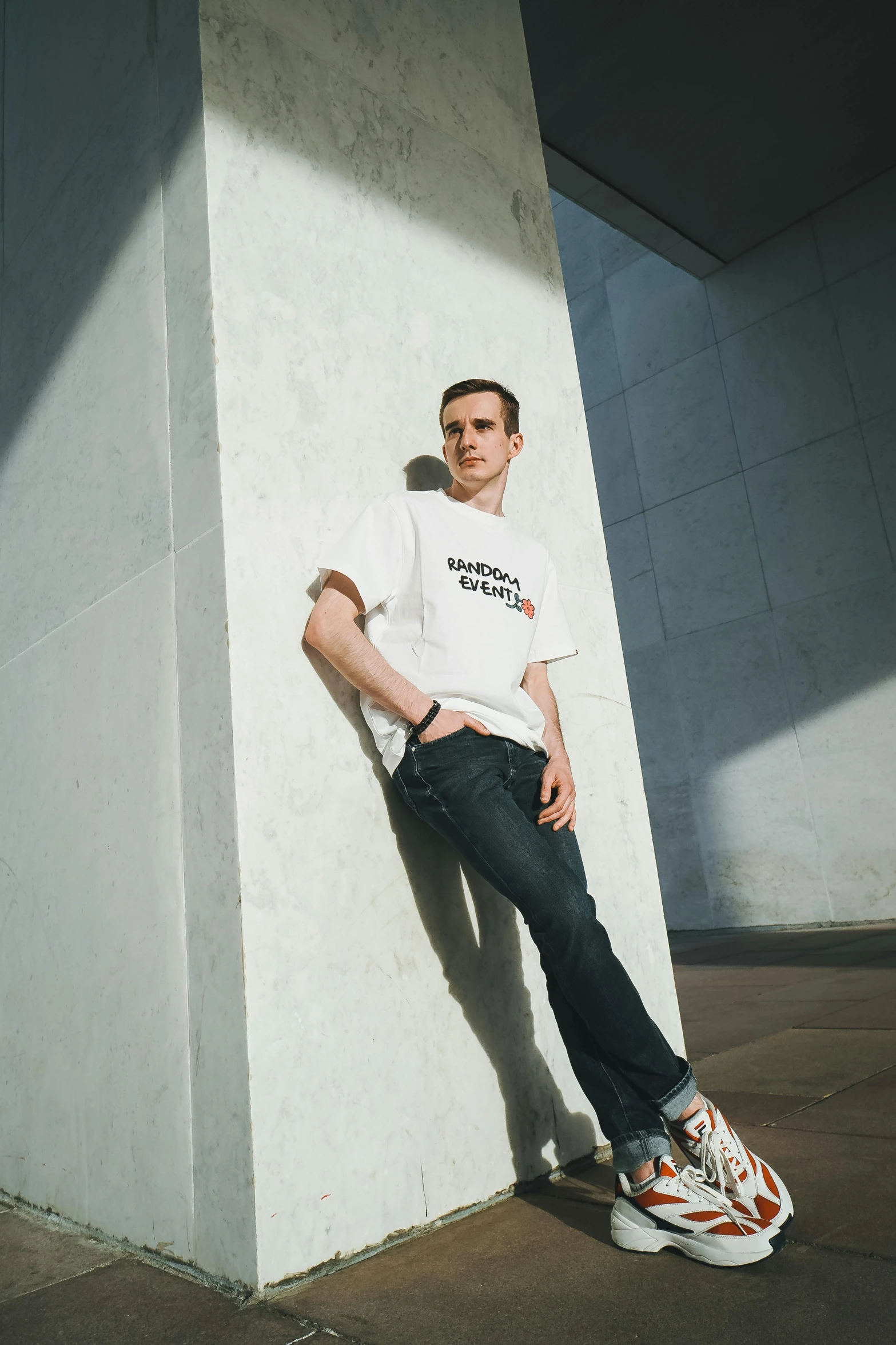 a man leaning against a wall with a skateboard, inspired by Jean Malouel, bauhaus, man in white t - shirt, vitalik buterin, hollywood promotional image, museum photoshot