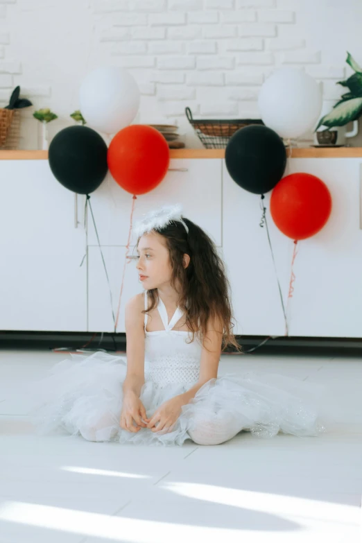 a little girl in a white dress sitting on the floor, pexels contest winner, black and red only, party balloons, ( ( theatrical ) ), in a kitchen