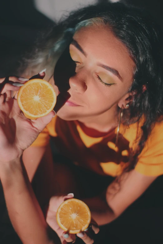 a woman holding two slices of oranges in front of her face, inspired by Elsa Bleda, trending on pexels, renaissance, smoking a joint, wearing yellow croptop, night time, 🐿🍸🍋