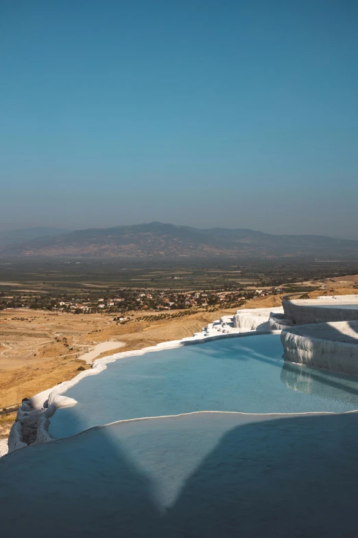 a pool of water with a mountain in the background, pamukkale, terraced orchards and ponds, hot tub, damascus