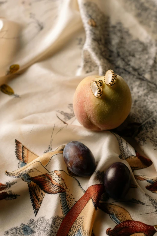 a couple of figurines sitting on top of a bed, a still life, inspired by Frederick Goodall, trending on pexels, baroque, butterfly jewelry, fruits, gilt silk fabric, detail shot