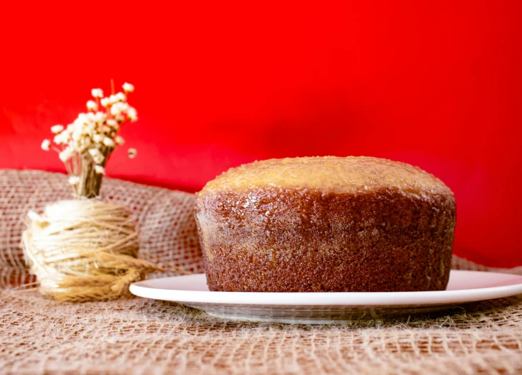 a cake sitting on top of a white plate, by Julia Pishtar, on a red background, bread, background image, sichuan