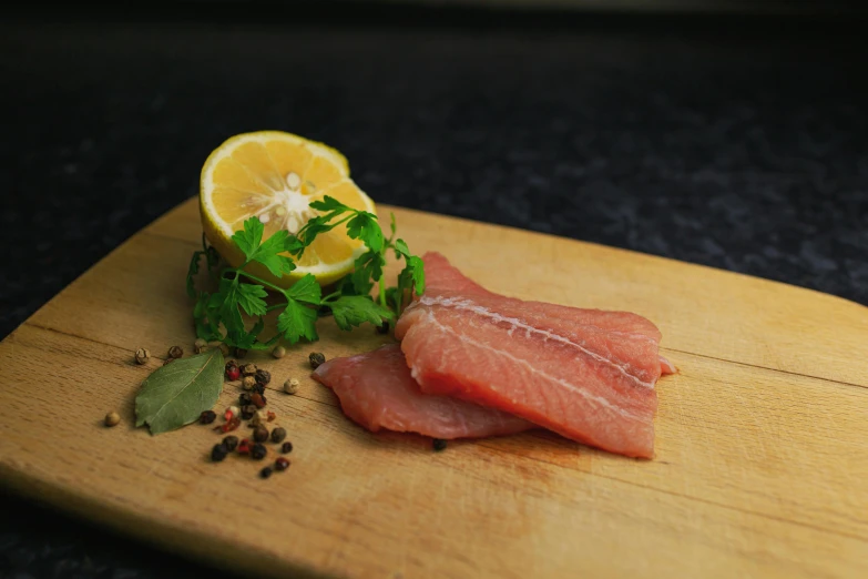 a piece of meat sitting on top of a wooden cutting board, a picture, unsplash, hurufiyya, arctic fish, lemon, medium height, taken from the high street