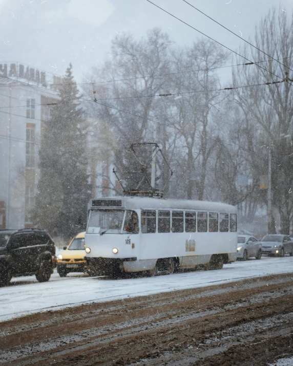 bus in traffic under electrical wires during snowfall