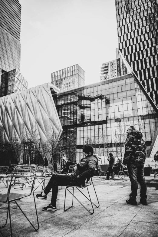 a couple of people that are sitting in chairs, a black and white photo, unsplash contest winner, temporary art, buildings made out of glass, against a winter garden, entertainment district, people watching