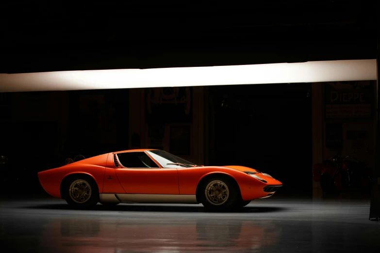 an orange sports car in a dark garage