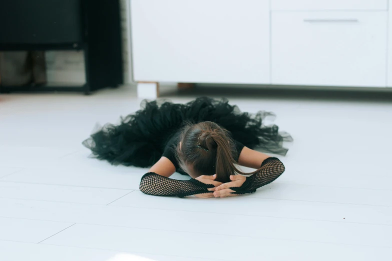 a woman in a black dress laying on the floor, by Julia Pishtar, pexels contest winner, arabesque, frustrated, wearing a tutu, gif, at home