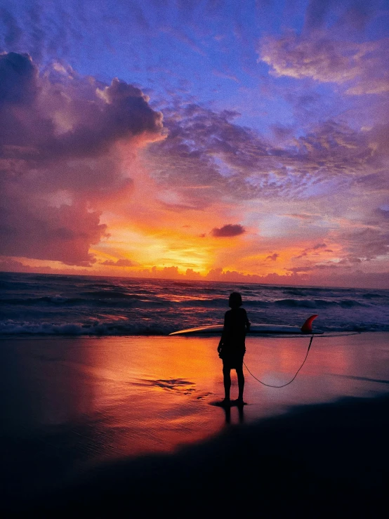 a person standing on a beach holding a surfboard, by Robbie Trevino, pexels contest winner, violet and yellow sunset, bali, fishing, today\'s featured photograph 4k