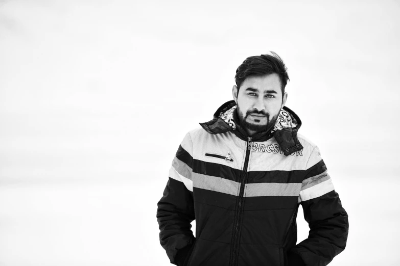 a man poses in front of an empty wall