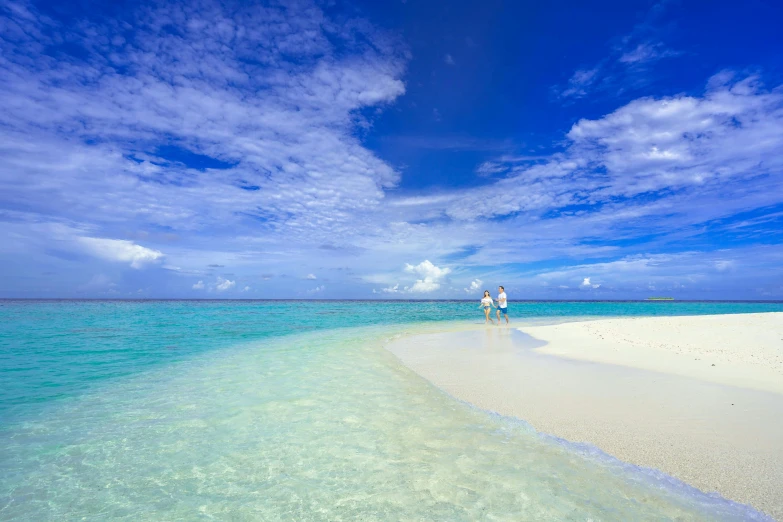 an ocean with people holding hands walking along the beach