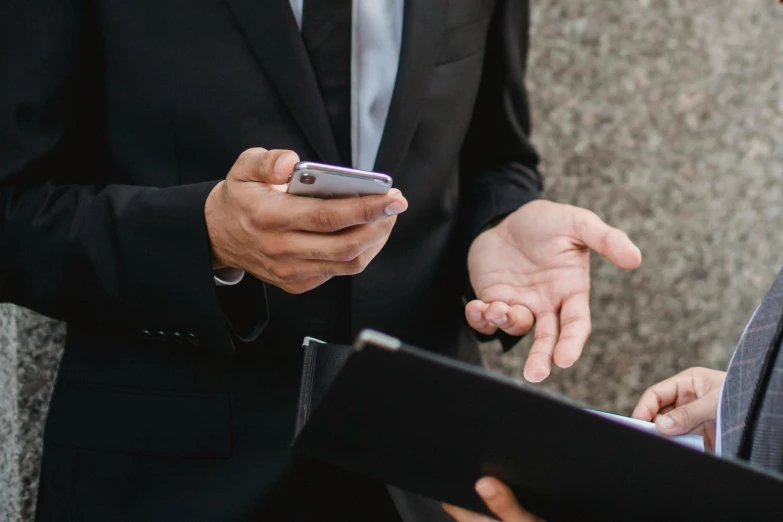 a couple of men standing next to each other, trending on pexels, corporate phone app icon, wearing black suit, holding a clipboard, mid shot