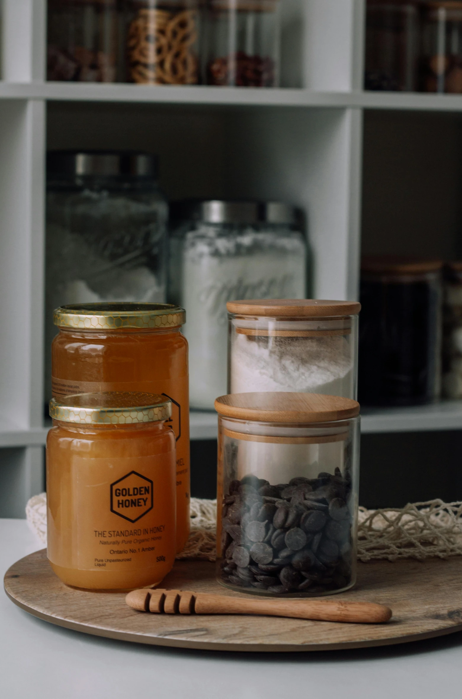 a couple of jars sitting on top of a wooden tray, pexels, honeycomb, jar on a shelf, tall shot, carbon