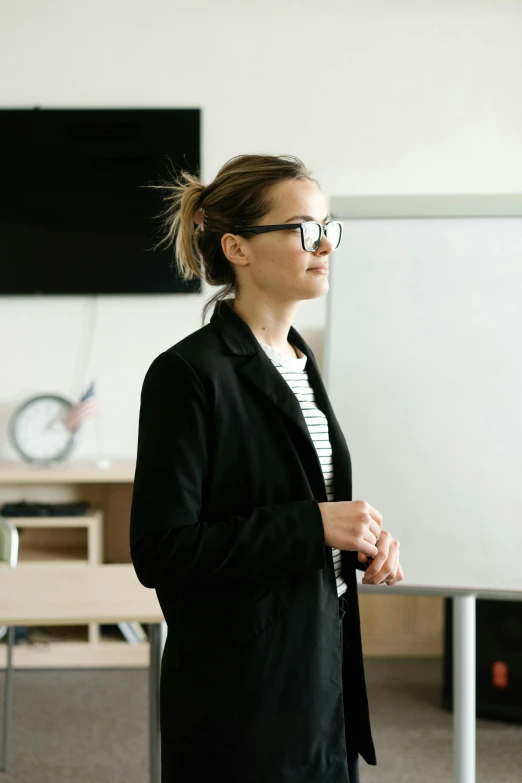 a woman standing in front of a white board, trending on unsplash, academic art, wearing causal black suits, nerdy appearance, standing in class, thoughtful )