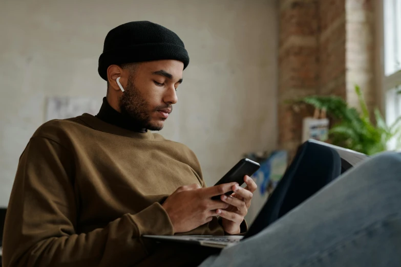 a man sitting on a couch using a cell phone, trending on pexels, sitting at a computer, he is wearing a brown sweater, essence, avatar image