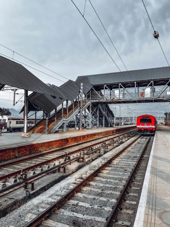 a red train traveling down train tracks next to a train station, profile image, architecture photo, square, view from back