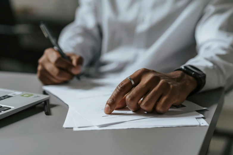 man in white shirt with a hand on top of paperwork