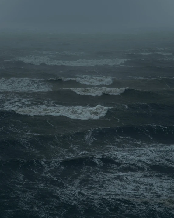 a large body of water under a cloudy sky, an album cover, pexels, romanticism, rough seas, it's getting dark, low pressure system, dark ambient album cover