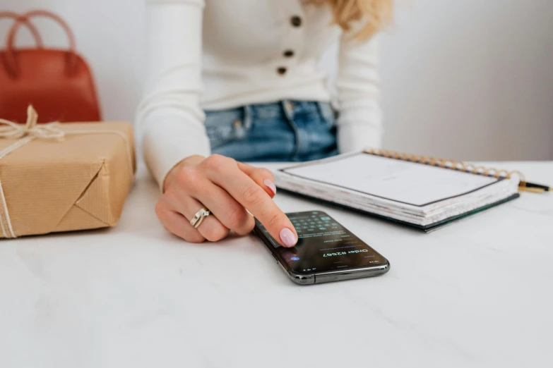 a woman sitting at a table with a cell phone, trending on pexels, inspect in inventory image, thumbnail, bottom angle, 1 2 9 7