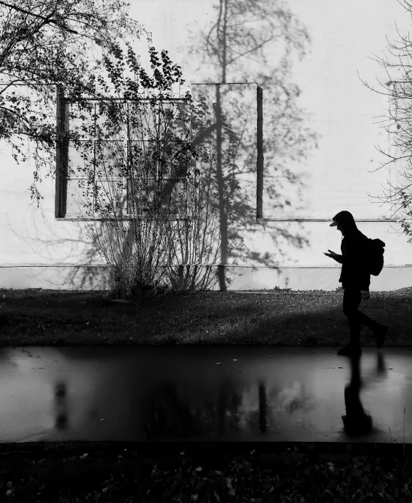 a woman is walking down a wet sidewalk