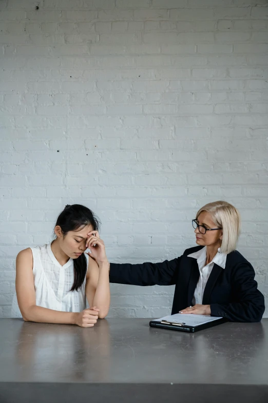 two women sitting at a table in front of a laptop, by Nina Hamnett, pexels contest winner, depressed dramatic bicep pose, greeting hand on head, charts, asian female