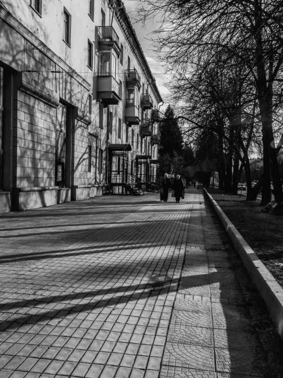 a black and white po of a sidewalk lined with brick buildings