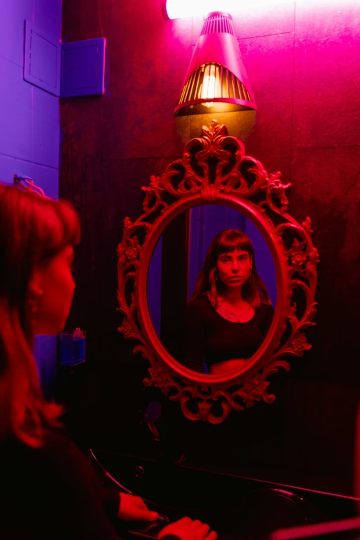 a woman looking at her reflection in a mirror, inspired by Nan Goldin, conceptual art, an escape room in a small, violet lighting, red and blue black light, production photo
