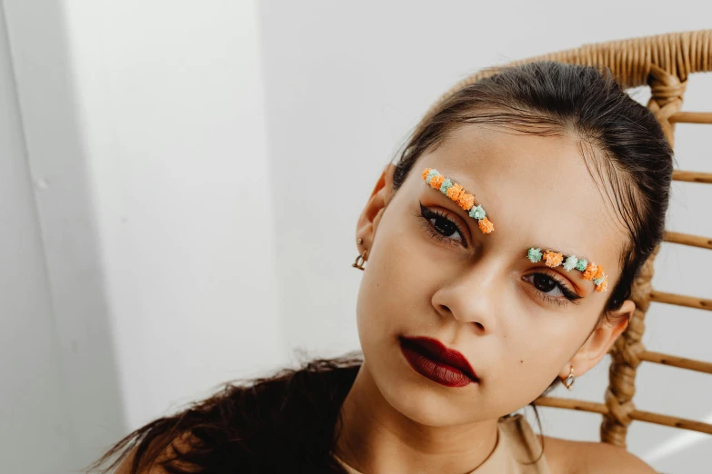 a woman sitting on top of a wicker chair, an album cover, trending on pexels, antipodeans, facepaint facepaint facepaint, covered in jewels, orange pupils, profile image