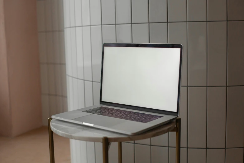 a laptop on a stool next to a wall